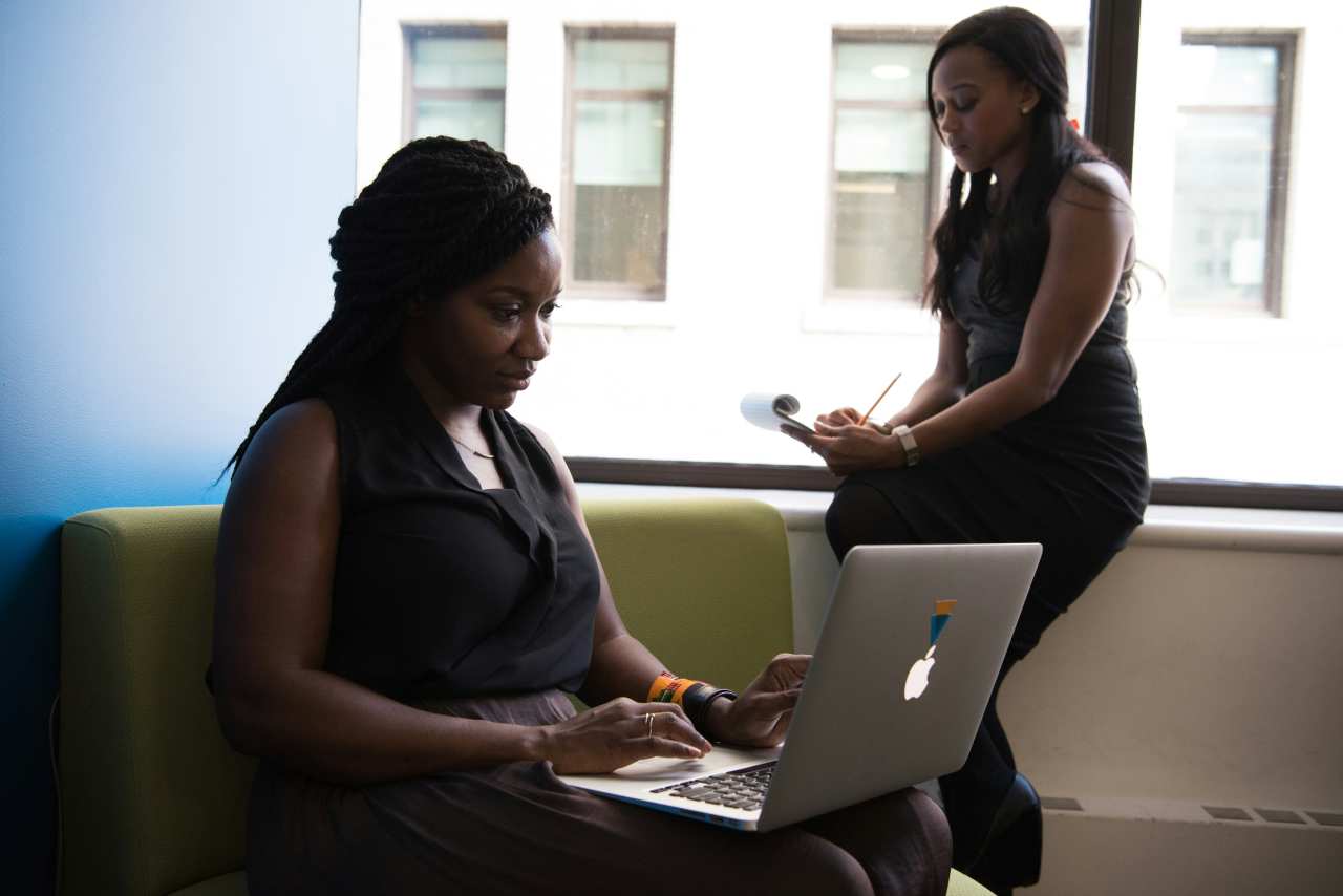 Two women working with a laptop and handwritten notes